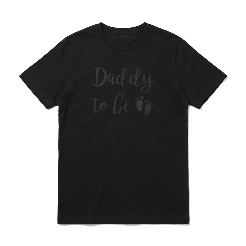 Daddy To Be Dad T-Shirt – Schriftzug Daddy to be mit zwei kleinen Fußabdrücken in Kursive – Klassisches T-Shirt in Schwarz